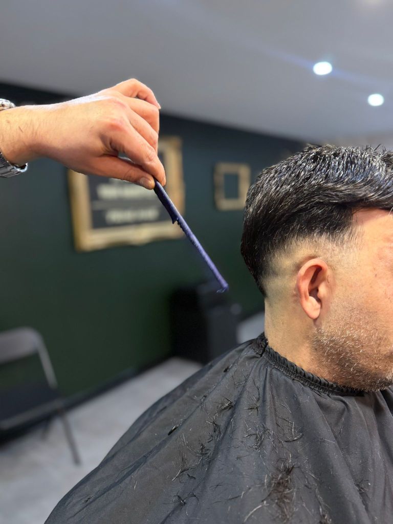 Professionele fade knipbeurt bij Barber Lounge Temse, vakkundige barber aan het werk met kam en schaar